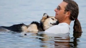 man-ligt-uren-met-zijn-hond-in-het-water-om-hem-te-laten-ontspannen